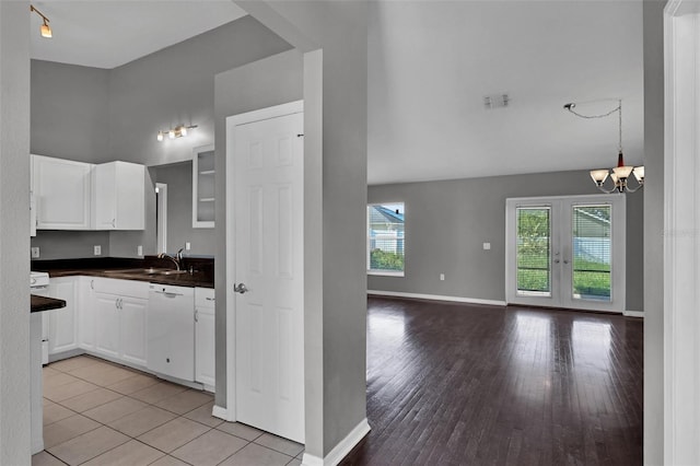 kitchen with sink, light hardwood / wood-style flooring, white cabinetry, white dishwasher, and a chandelier