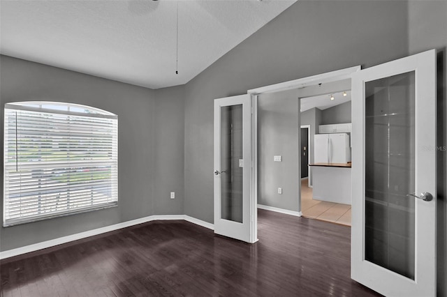 unfurnished bedroom with lofted ceiling, white refrigerator, wood-type flooring, a textured ceiling, and french doors