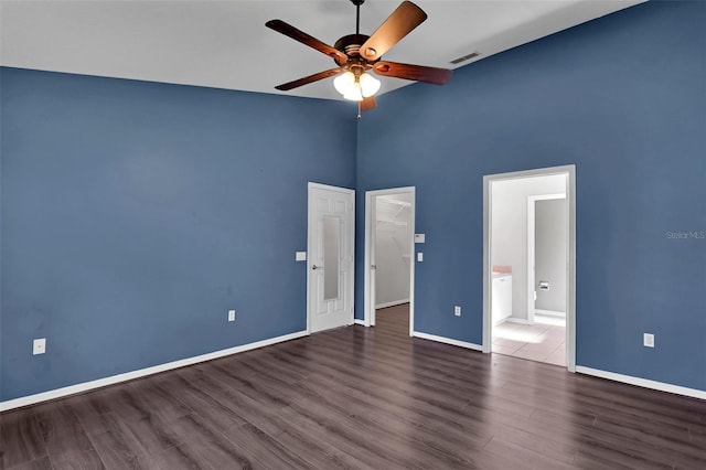 unfurnished bedroom featuring a walk in closet, dark wood-type flooring, and ceiling fan