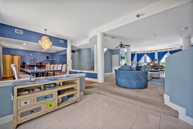 tiled living room featuring ceiling fan with notable chandelier and a textured ceiling