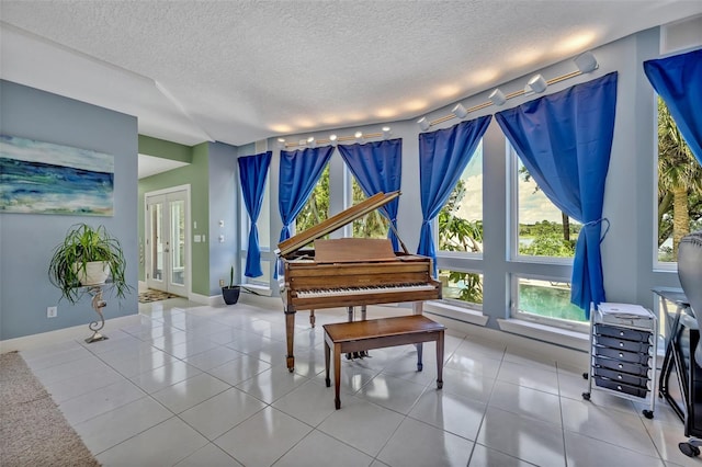 miscellaneous room with light tile patterned floors, french doors, a textured ceiling, and rail lighting