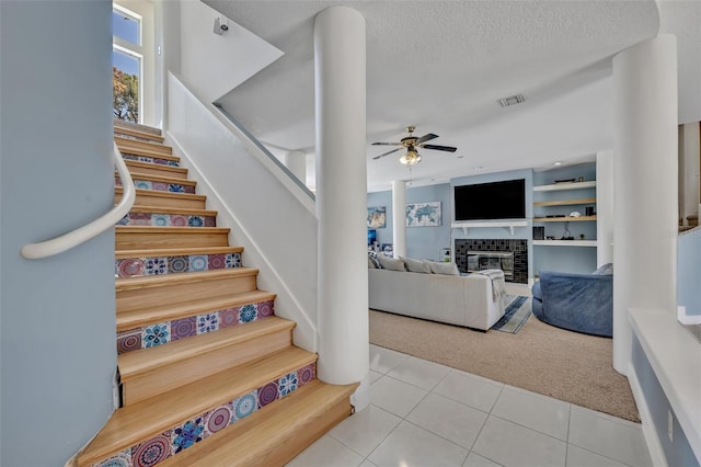 stairway featuring ceiling fan, built in features, tile patterned floors, and a textured ceiling