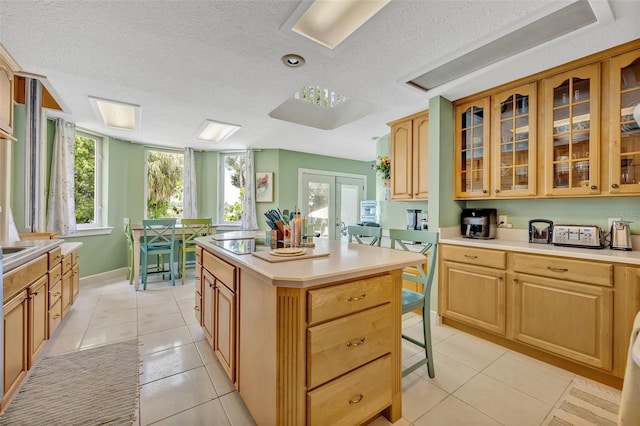 kitchen with light tile patterned floors, a kitchen island, a healthy amount of sunlight, and a breakfast bar area