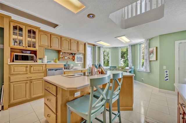 kitchen featuring light tile patterned floors, a center island, stainless steel appliances, and a breakfast bar area