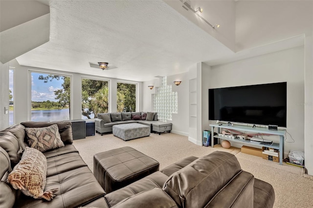 carpeted living room with a water view and a textured ceiling