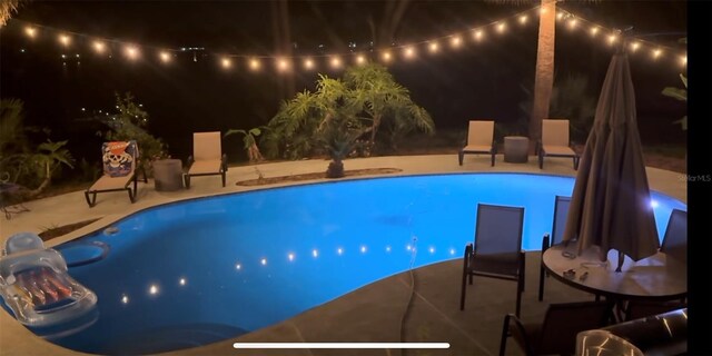 pool at twilight featuring a patio area