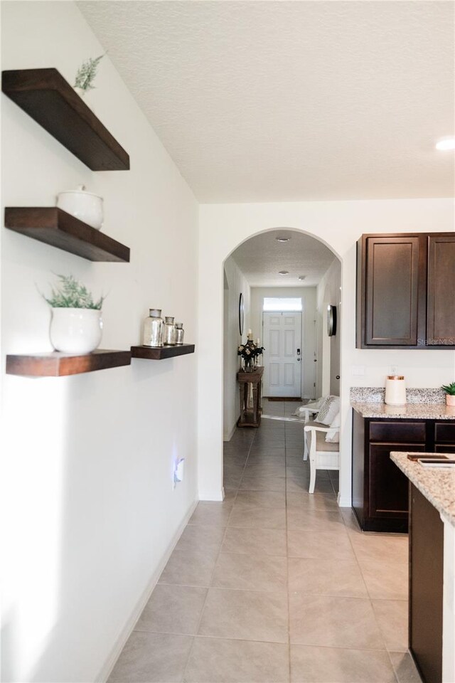 kitchen featuring light tile patterned flooring and dark brown cabinetry