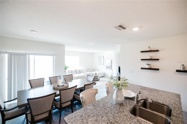 dining space featuring sink, a textured ceiling, and tile patterned floors