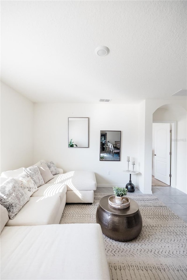 tiled living room featuring a textured ceiling