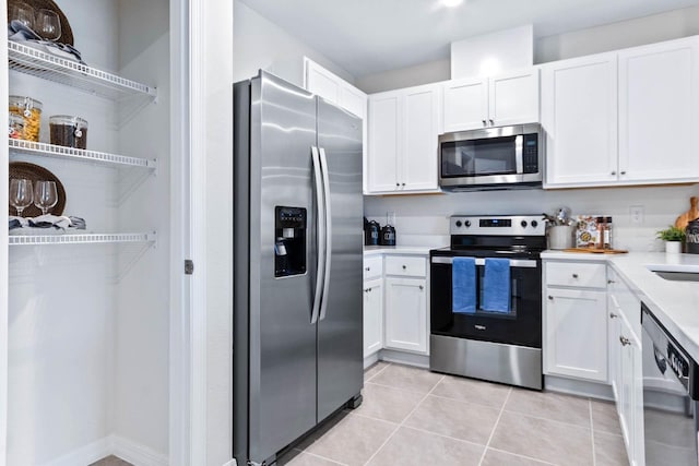 kitchen with light tile patterned floors, appliances with stainless steel finishes, sink, and white cabinetry