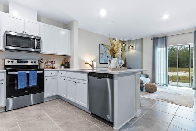 kitchen with kitchen peninsula, appliances with stainless steel finishes, white cabinetry, and sink