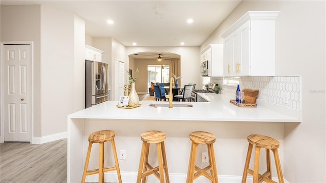 kitchen with a kitchen bar, white cabinetry, kitchen peninsula, and stainless steel appliances