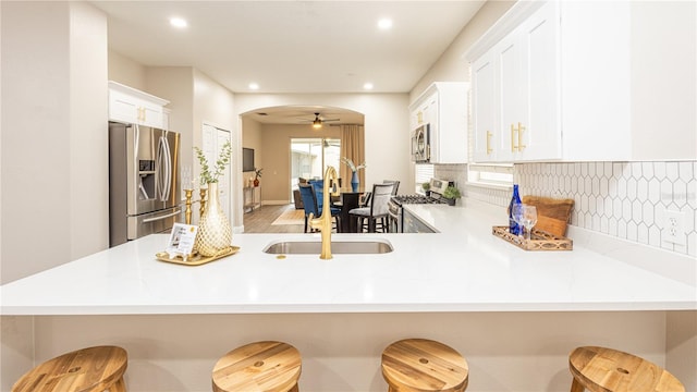 kitchen with a kitchen bar, appliances with stainless steel finishes, kitchen peninsula, and ceiling fan