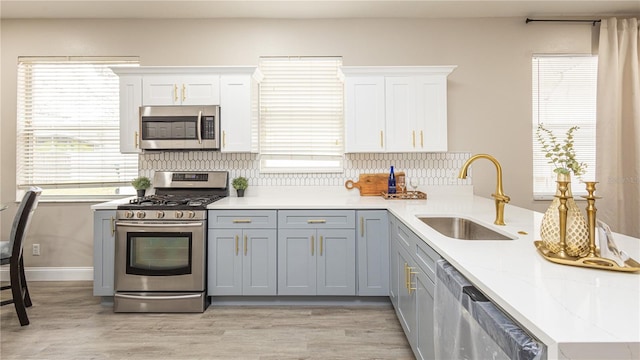 kitchen featuring kitchen peninsula, sink, stainless steel appliances, and white cabinetry