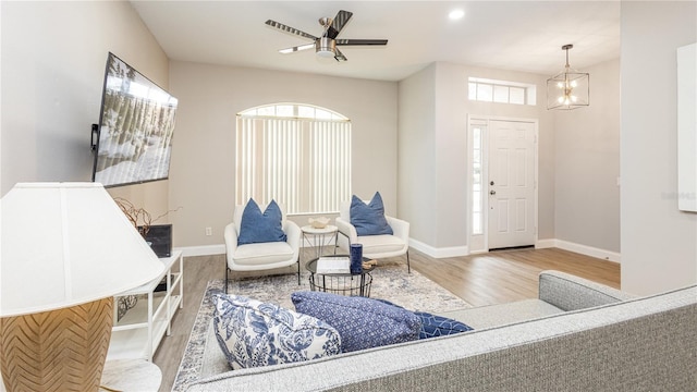 living room with ceiling fan with notable chandelier and hardwood / wood-style flooring