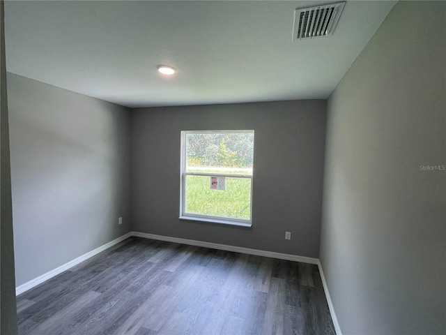 unfurnished room featuring baseboards, visible vents, and dark wood-style flooring