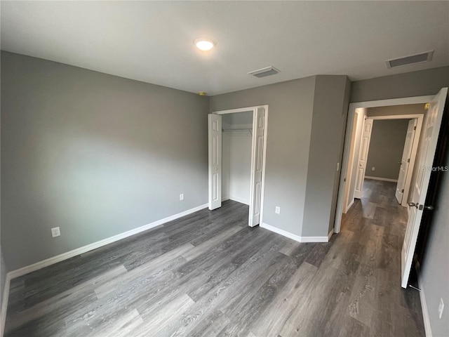 unfurnished bedroom with dark hardwood / wood-style floors and a closet