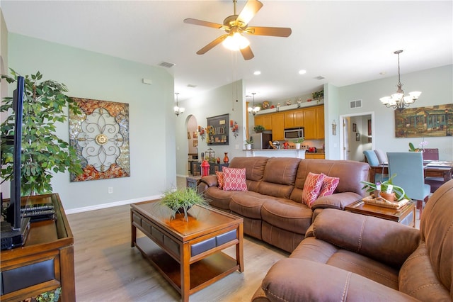 living room with ceiling fan with notable chandelier and light hardwood / wood-style flooring