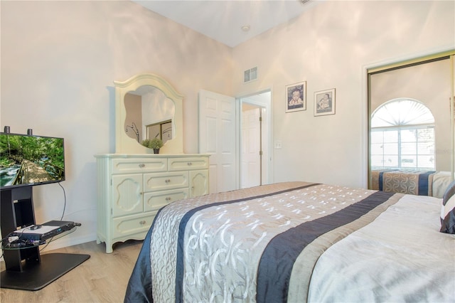 bedroom with light hardwood / wood-style floors and a towering ceiling