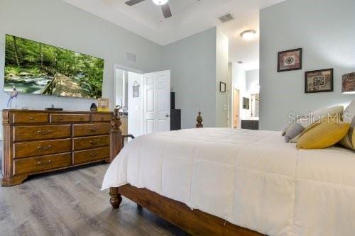 bedroom with hardwood / wood-style flooring, ensuite bathroom, and ceiling fan