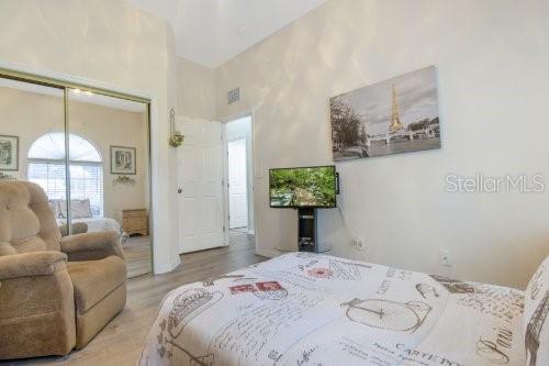 bedroom featuring a closet, light hardwood / wood-style floors, and a towering ceiling