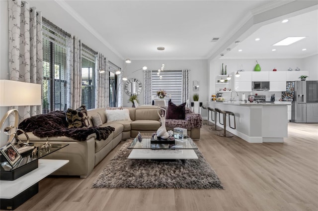 living room featuring sink, light hardwood / wood-style flooring, and ornamental molding