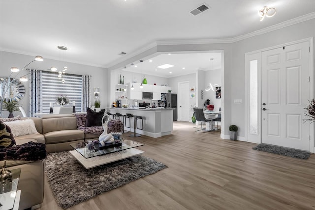 living room featuring light hardwood / wood-style floors, sink, and ornamental molding