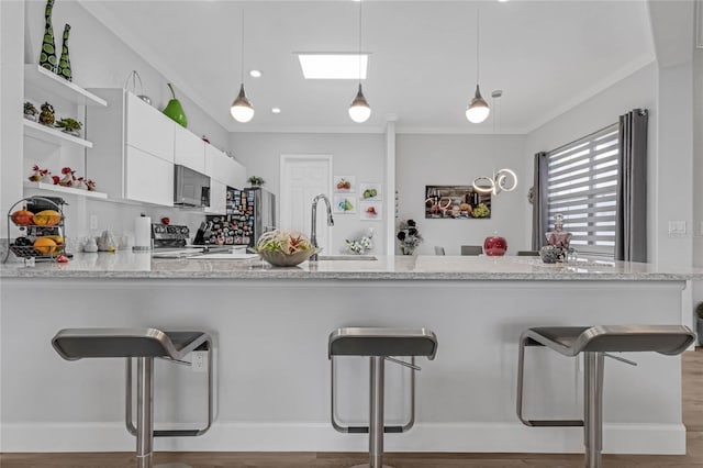 kitchen featuring kitchen peninsula, a kitchen bar, and white cabinets