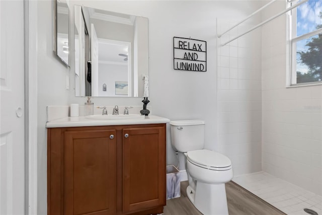 bathroom featuring vanity, wood-type flooring, crown molding, a tile shower, and toilet