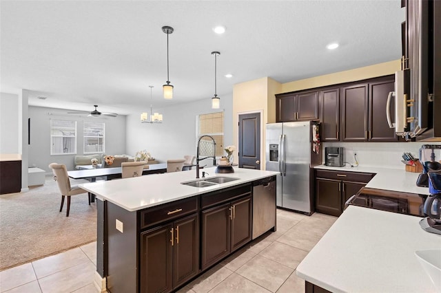 kitchen with dark brown cabinetry, sink, decorative light fixtures, a center island with sink, and stainless steel appliances