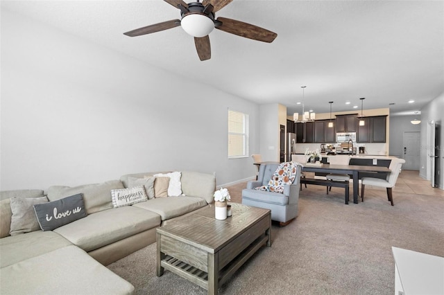 carpeted living room with ceiling fan with notable chandelier