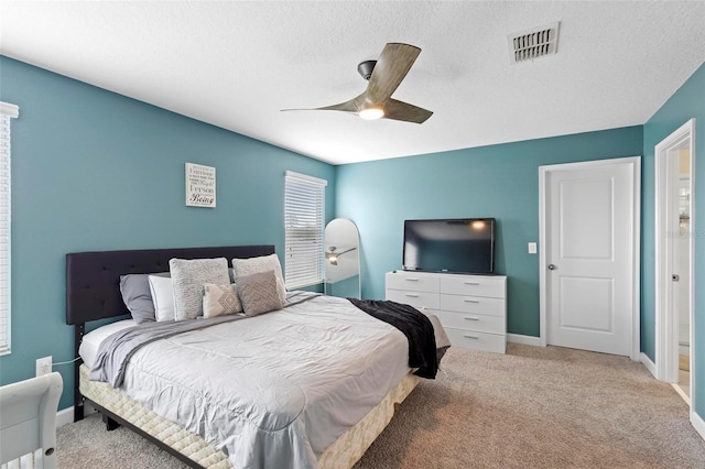 bedroom featuring light carpet, ceiling fan, and a textured ceiling