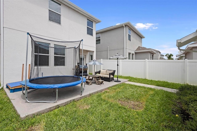 rear view of house with a patio, a trampoline, and a lawn