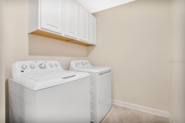 laundry area featuring cabinets, washing machine and dryer, and light tile patterned floors