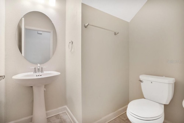 bathroom featuring vaulted ceiling, tile patterned flooring, and toilet