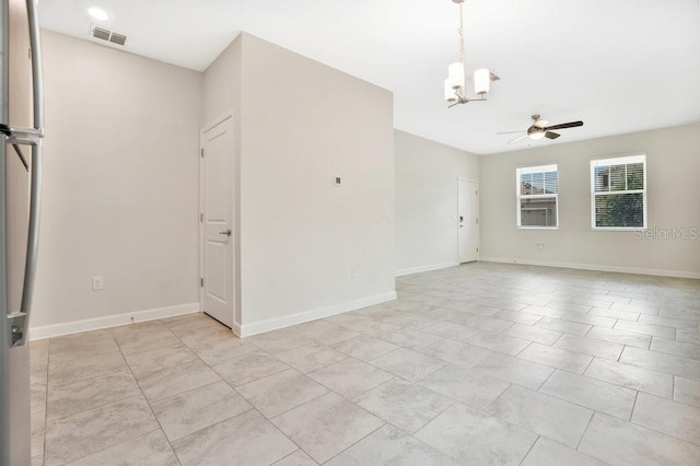 tiled empty room with ceiling fan with notable chandelier