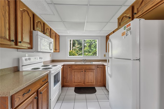 kitchen featuring light tile patterned flooring, sink, a paneled ceiling, and white appliances