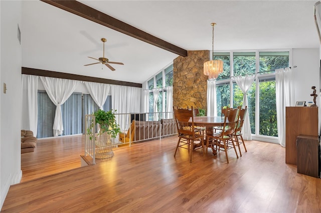 dining room with ceiling fan with notable chandelier, floor to ceiling windows, hardwood / wood-style floors, and vaulted ceiling with beams