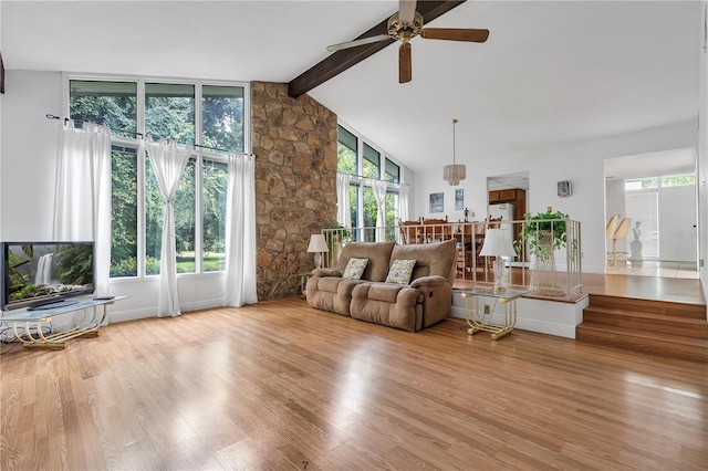 living room with a healthy amount of sunlight, vaulted ceiling with beams, and light wood-type flooring