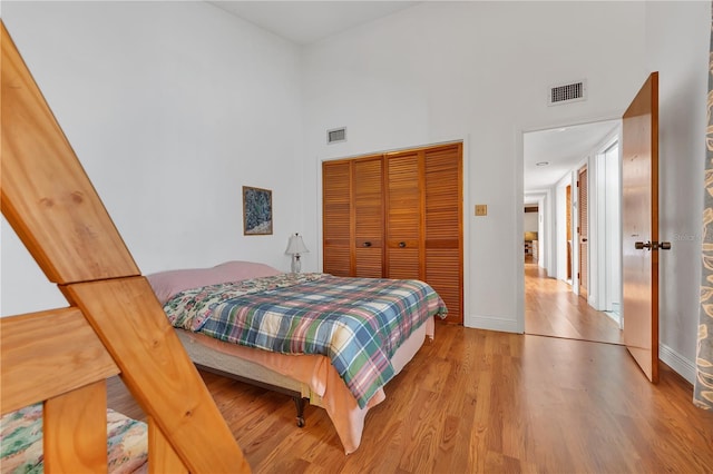 bedroom with a towering ceiling, hardwood / wood-style floors, and a closet