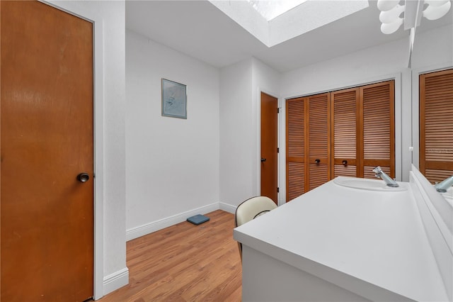 laundry room featuring a skylight, sink, and light hardwood / wood-style flooring