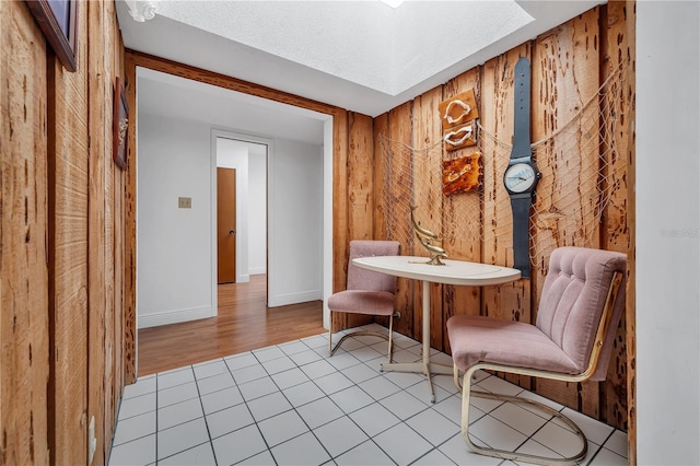 living area featuring light tile patterned flooring and wood walls