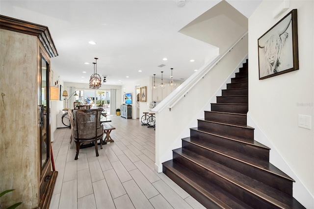 stairway featuring a notable chandelier