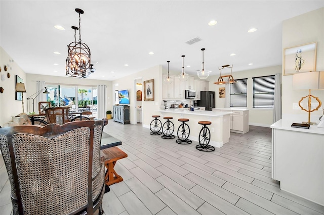interior space with visible vents, baseboards, wood finish floors, recessed lighting, and an inviting chandelier