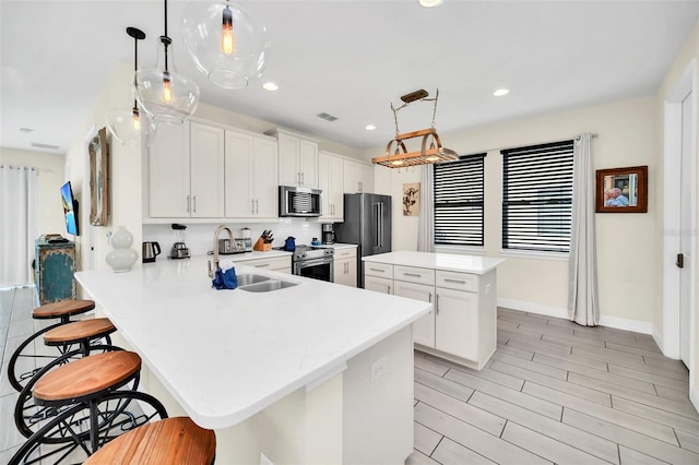 kitchen featuring a breakfast bar, light countertops, stainless steel appliances, and a kitchen island