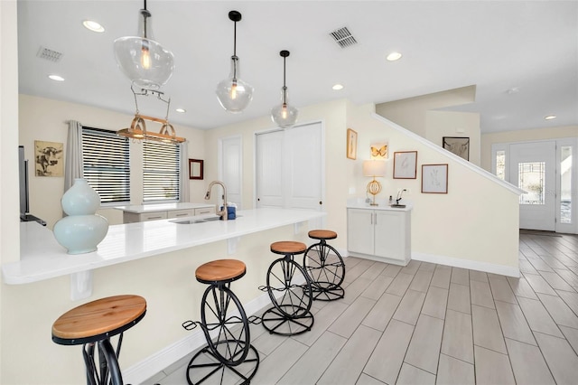 kitchen with a sink, a breakfast bar area, visible vents, and a peninsula