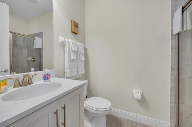 full bathroom featuring a stall shower, baseboards, toilet, and vanity