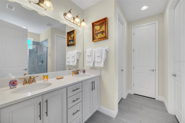 full bathroom featuring double vanity, a sink, a stall shower, and visible vents