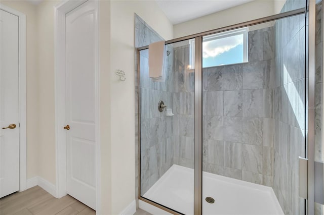full bath with baseboards, wood finished floors, and a shower stall