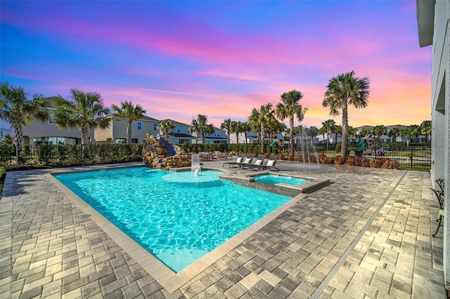 pool with a hot tub, fence, and a patio